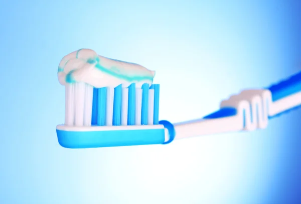 Bürste für Zahnpasta in der Hand des Mädchens auf blauem Hintergrund — Stockfoto