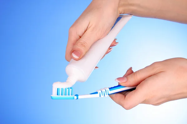 Tandpasta en penseel in de hand op blauwe achtergrond — Stockfoto