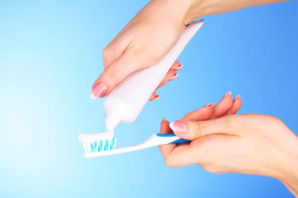 Tooth-paste and brush in the hand on blue background