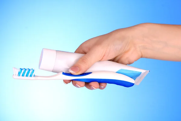 Tandpasta en penseel in de hand op blauwe achtergrond — Stockfoto
