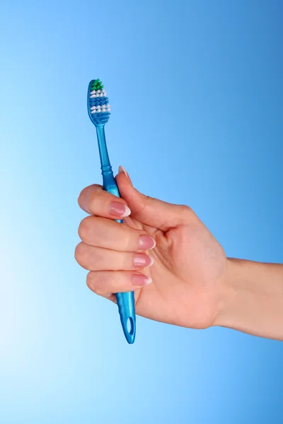 Szczotka do zębów w w dziewczynkę za rękę na niebieskim tle — Zdjęcie stockowe