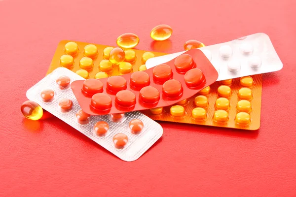 Pílulas medicamento pack pilha closeup no fundo vermelho — Fotografia de Stock