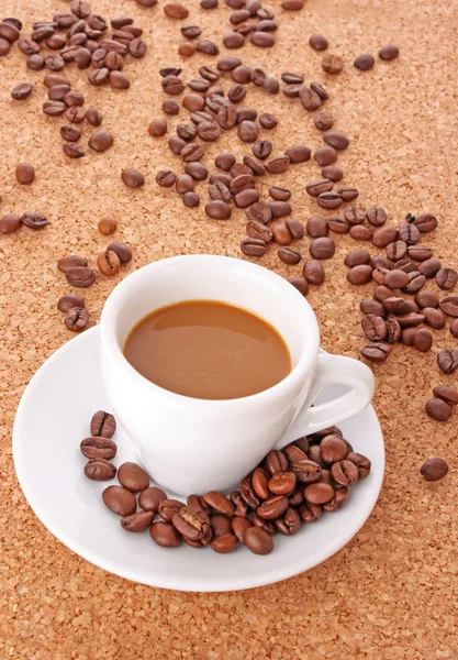 茶色の背景にコーヒー穀物コーヒーの小さな白いカップ — ストック写真