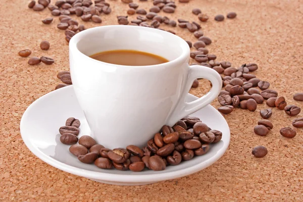 Liten vit kopp kaffe med kaffe korn på brun ba — Stockfoto