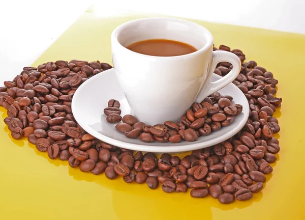 Kleine witte kopje koffie met koffie graan op gele achtergrond — Stockfoto