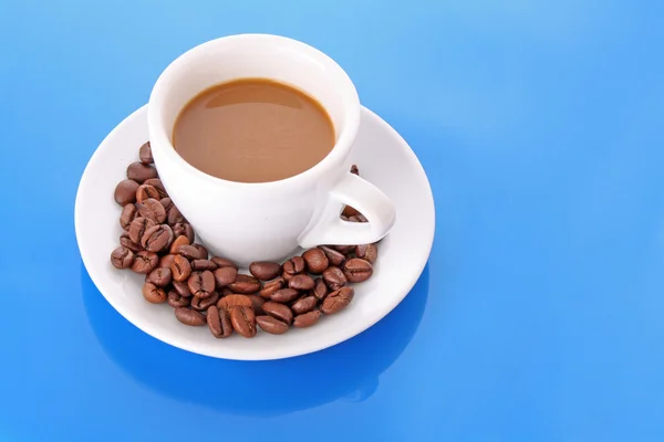 Petite tasse blanche de café avec grain de café sur fond bleu — Photo