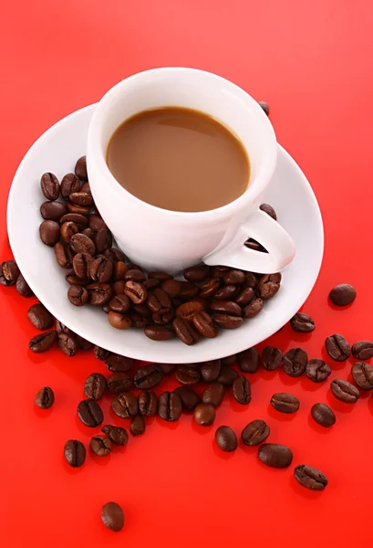 Λευκό φλιτζανάκι του καφέ με κόκκους καφέ σε κόκκινο φόντο — Φωτογραφία Αρχείου