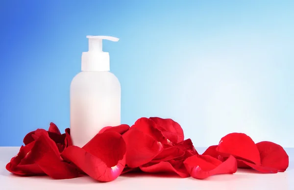 Tub with a cream with a red rose petals on blue background — Stock Photo, Image