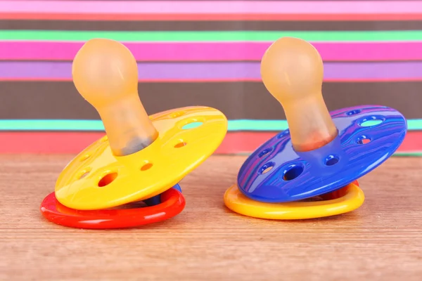 Baby-Silikonschnuller in blauer, roter und gelber Farbe, auf Farbe — Stockfoto