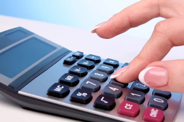 Fingers and calculator on blue background — Stock Photo, Image
