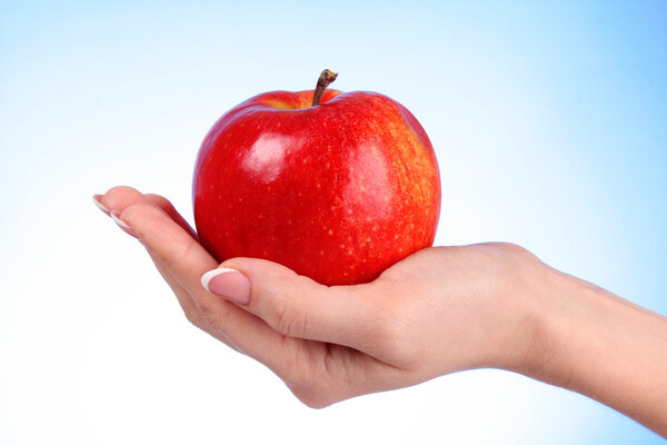 An apple on the hand on blue background