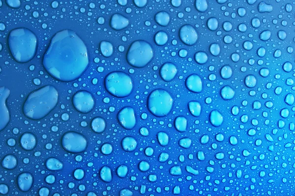 Голубые капли воды на фоне больших и малых капель — стоковое фото