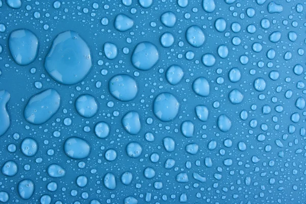 Синя вода падає на тло з великими і малими краплями — стокове фото