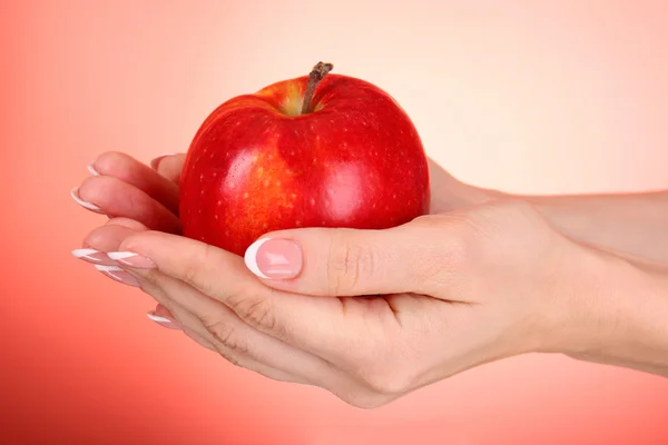 Яблуко на руці на червоному тлі — стокове фото