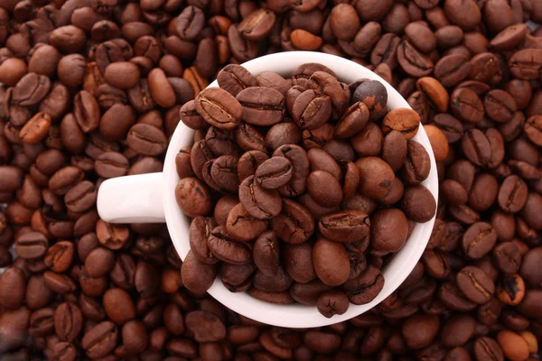 Cangkir putih kecil kopi dengan biji kopi di latar belakang biji-bijian — Stok Foto