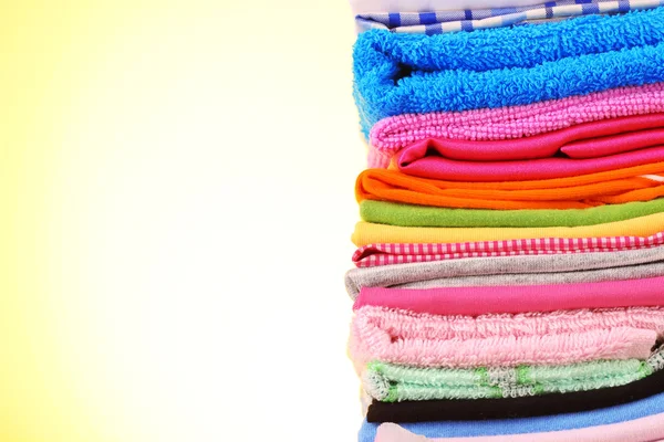 stock image Pile of colorful clothes on yellow background