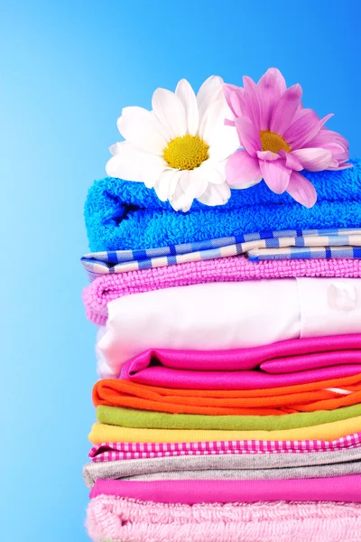 Montón de ropa colorida y flores sobre fondo azul — Foto de Stock