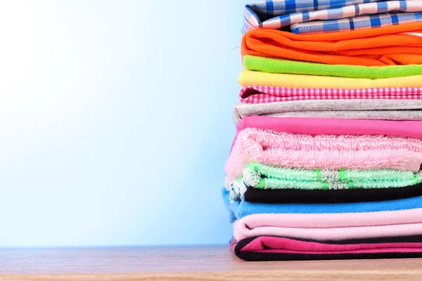 Pile of colorful clothes over blue background — Stock Photo, Image