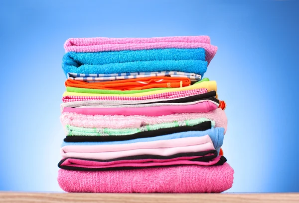 Pile of colorful clothes over blue background — Stock Photo, Image