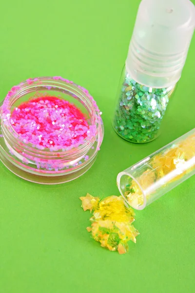 Color spangles for manicure on green background — Stock Photo, Image