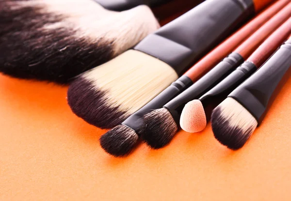 Cosmetic brushes on the orange background — Stock Photo, Image