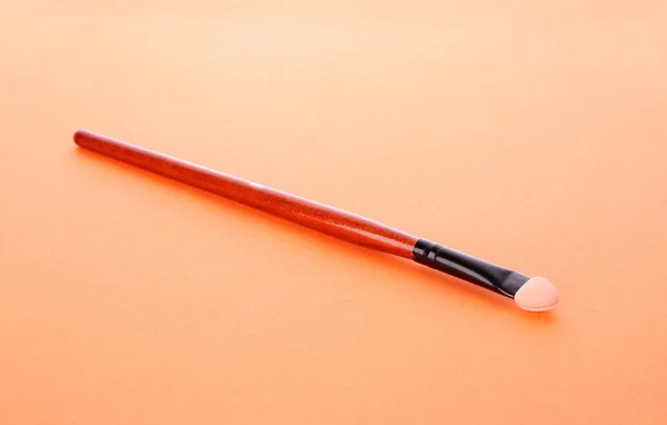 Escova cosmética no fundo laranja — Fotografia de Stock