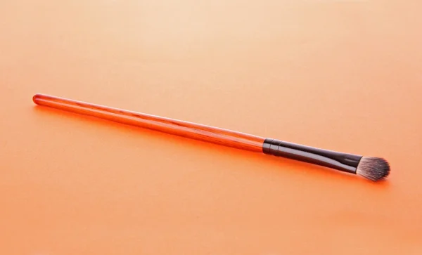 Escova cosmética no fundo laranja — Fotografia de Stock