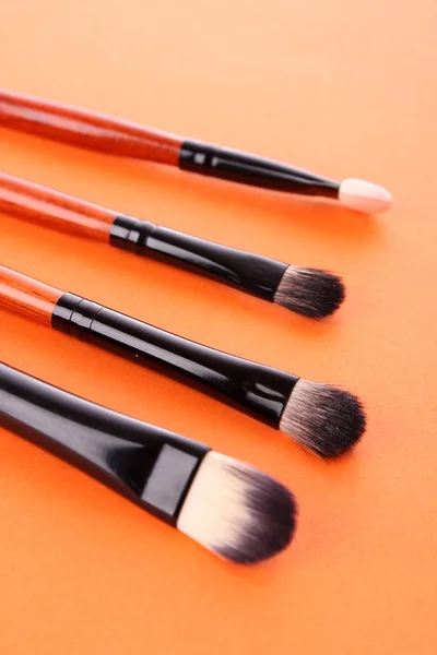 Kosmetiska borstar på orange bakgrund — Stockfoto