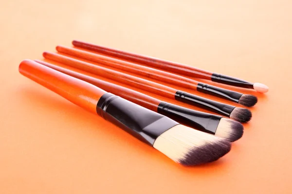 Cosmetic brushes on orange background — Stock Photo, Image