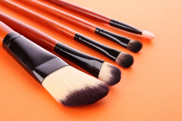 Escovas cosméticas no fundo laranja — Fotografia de Stock