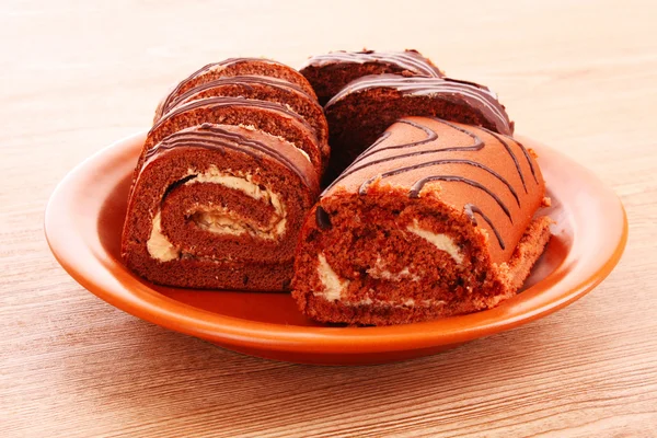 Swiss roll on the dish on wooden background — Stock Photo, Image