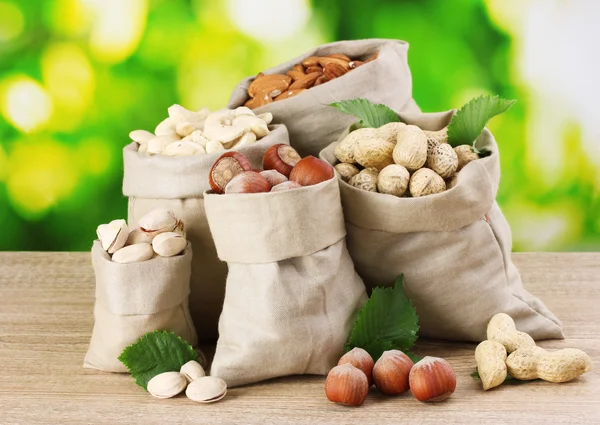 Variété de noix dans des sacs sur fond vert — Photo