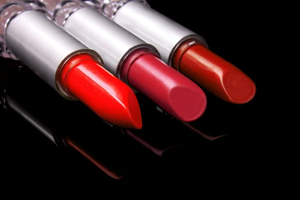 Three bright lipsticks on a black background — Stock Photo, Image