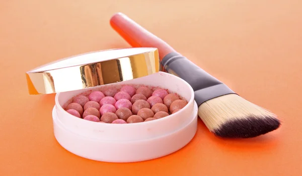 Rouge and brush on the orange background Stock Picture