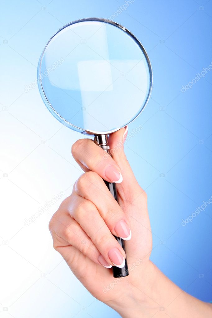 Woman hand with magnifier on blue background