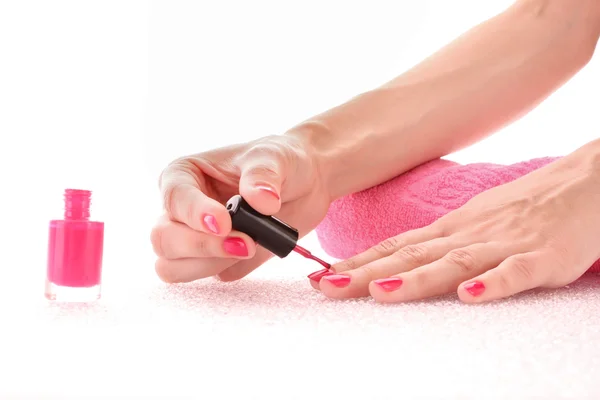 Woman applying pink nail polish