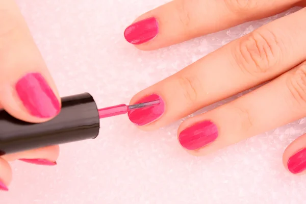 Mujer aplicando esmalte de uñas rosa — Foto de Stock