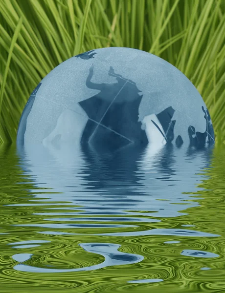 Blue glass globe in grass with water — Stock Photo, Image