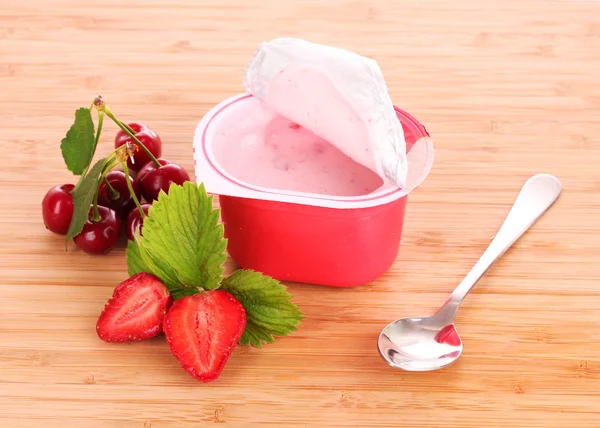 Jogurt a jahody na dřevěné pozadí — Stock fotografie
