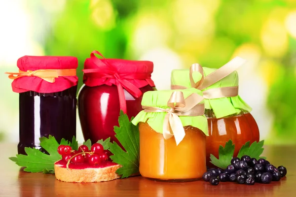 Chutné berry a džem z ovoce a bobule na zeleném pozadí — Stock fotografie