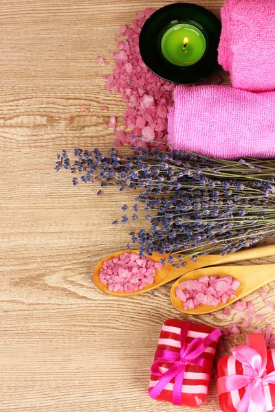 Prachtige lavendel kaars, zout, zeep en handdoek op houten achtergrond — Stockfoto