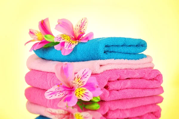 Stacked colorful towels on yellow background — Stock Photo, Image
