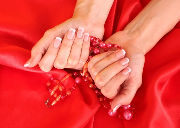 Hermosas manos de mujer con manicura francesa sobre fondo rojo —  Fotos de Stock