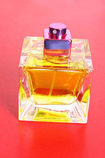 Parfumfles op rode achtergrond — Stockfoto