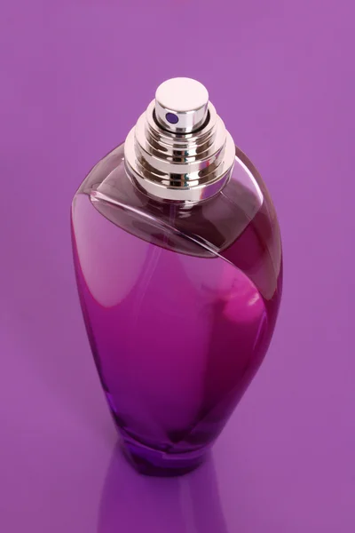 Бутылка духов на фиолетовом фоне — стоковое фото