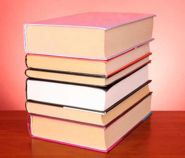 Livros pilha sobre a mesa e fundo vermelho — Fotografia de Stock
