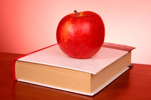 Книги и яблоко на красном фоне — стоковое фото
