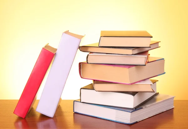 Books pile on the table and yellow background — Stock Photo, Image