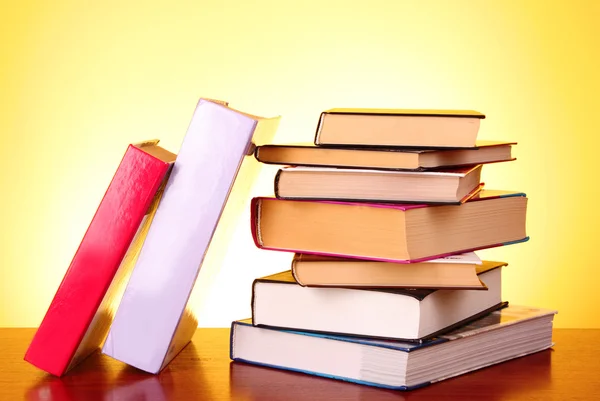 Hromada knih na stole a žlutým pozadím — Stock fotografie