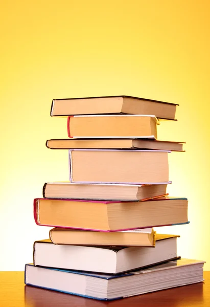 Stos książek na stole i żółte tło — Zdjęcie stockowe
